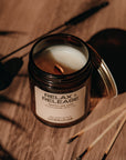 Candle in a jar labeled 'Relax + Release' on a wooden surface with shadows.