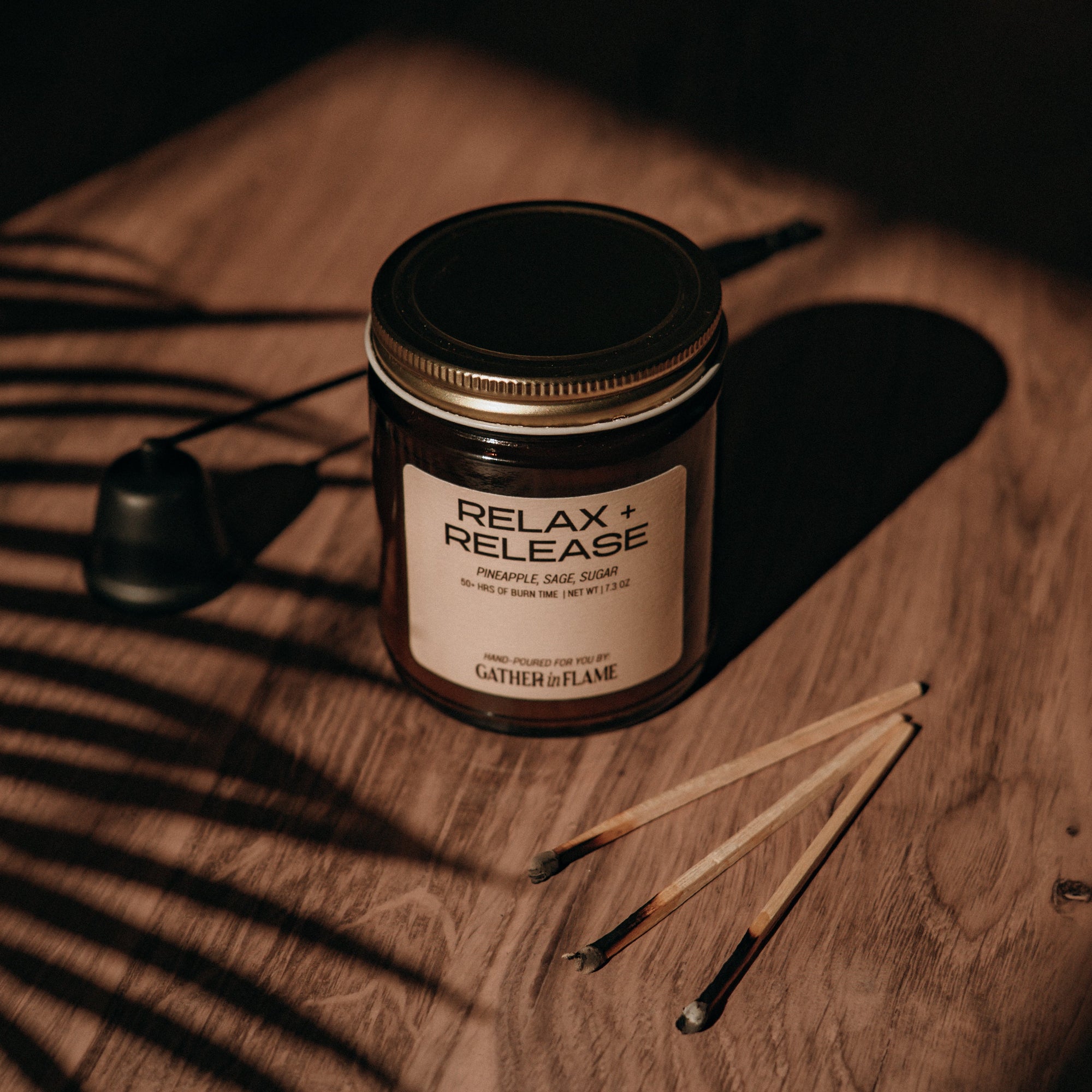 Candle labeled 'Relax &amp; Release' on a wooden surface with a dark background