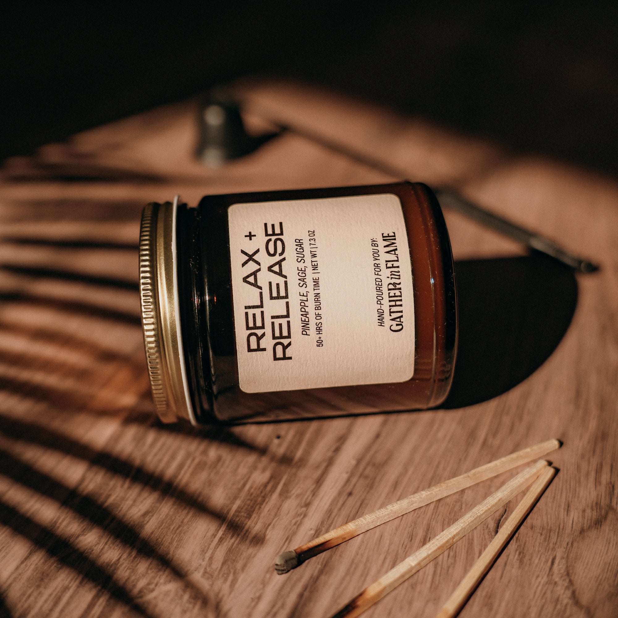 Jar labeled 'Relax + Release' on a wooden surface with matches beside it