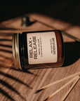 Jar labeled 'Relax + Release' on a wooden surface with matches beside it