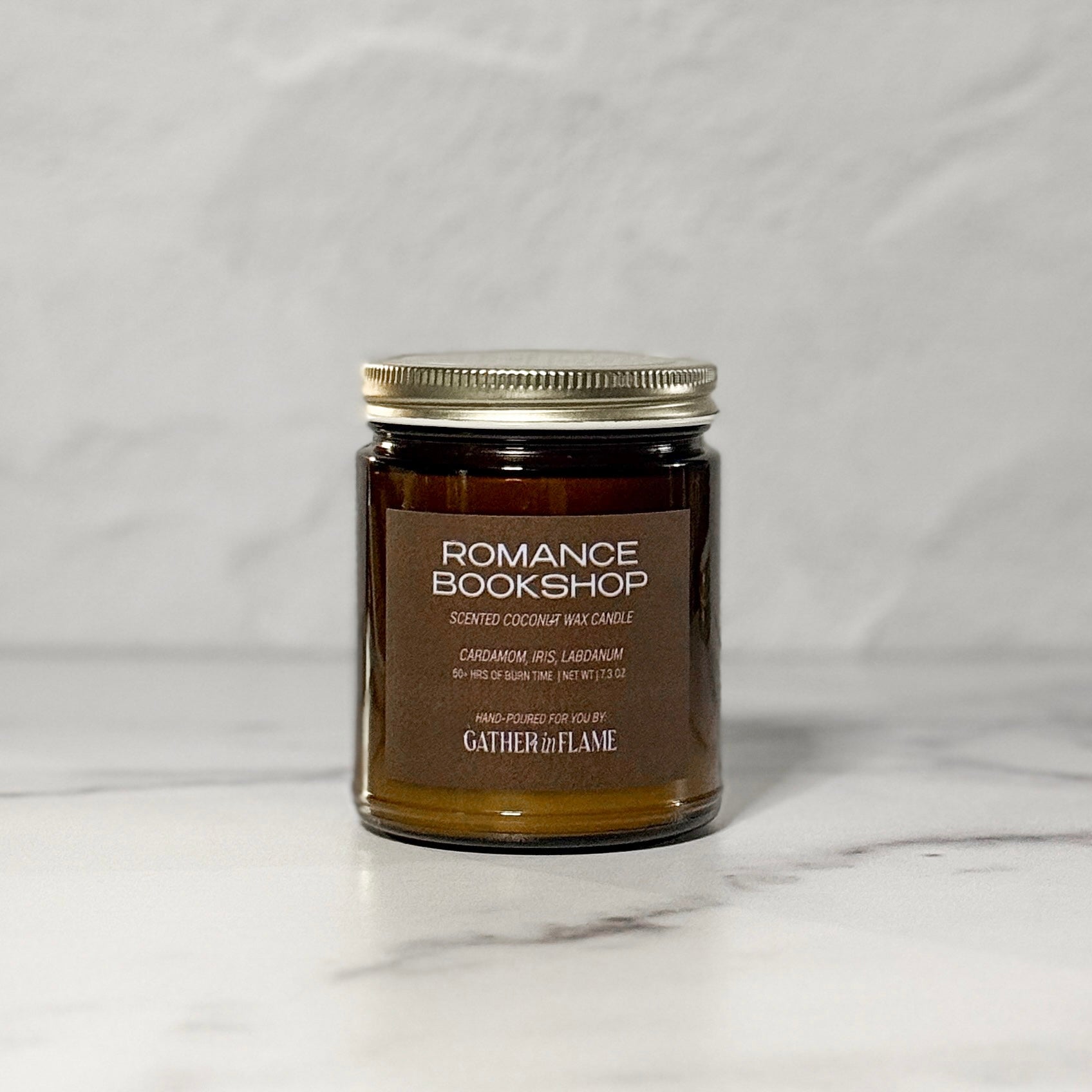 Amber glass jar candle labeled Romance Bookshop with a white background.