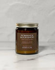 Amber glass jar candle labeled Romance Bookshop with a white background.