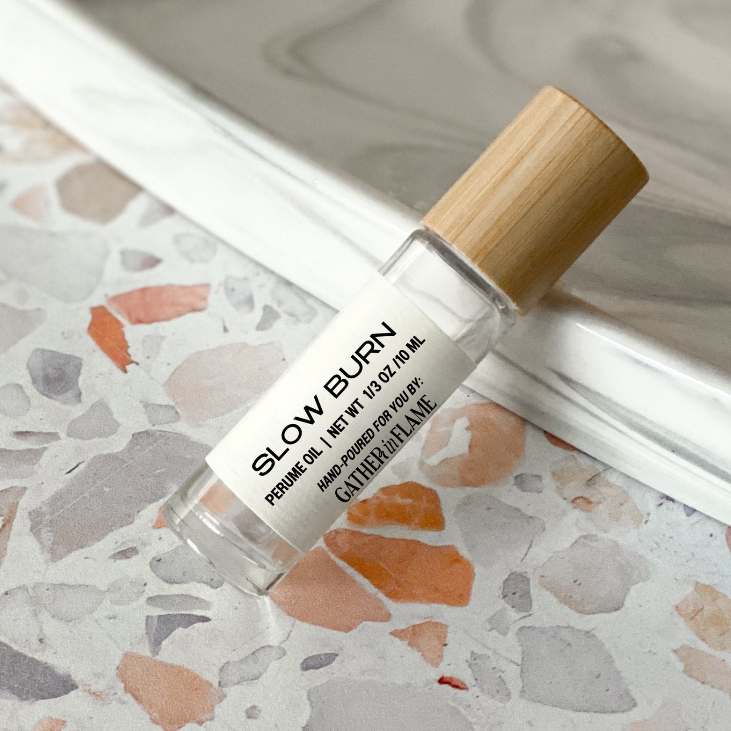perfume roller labeled Slow Burn on a terrazzo surface