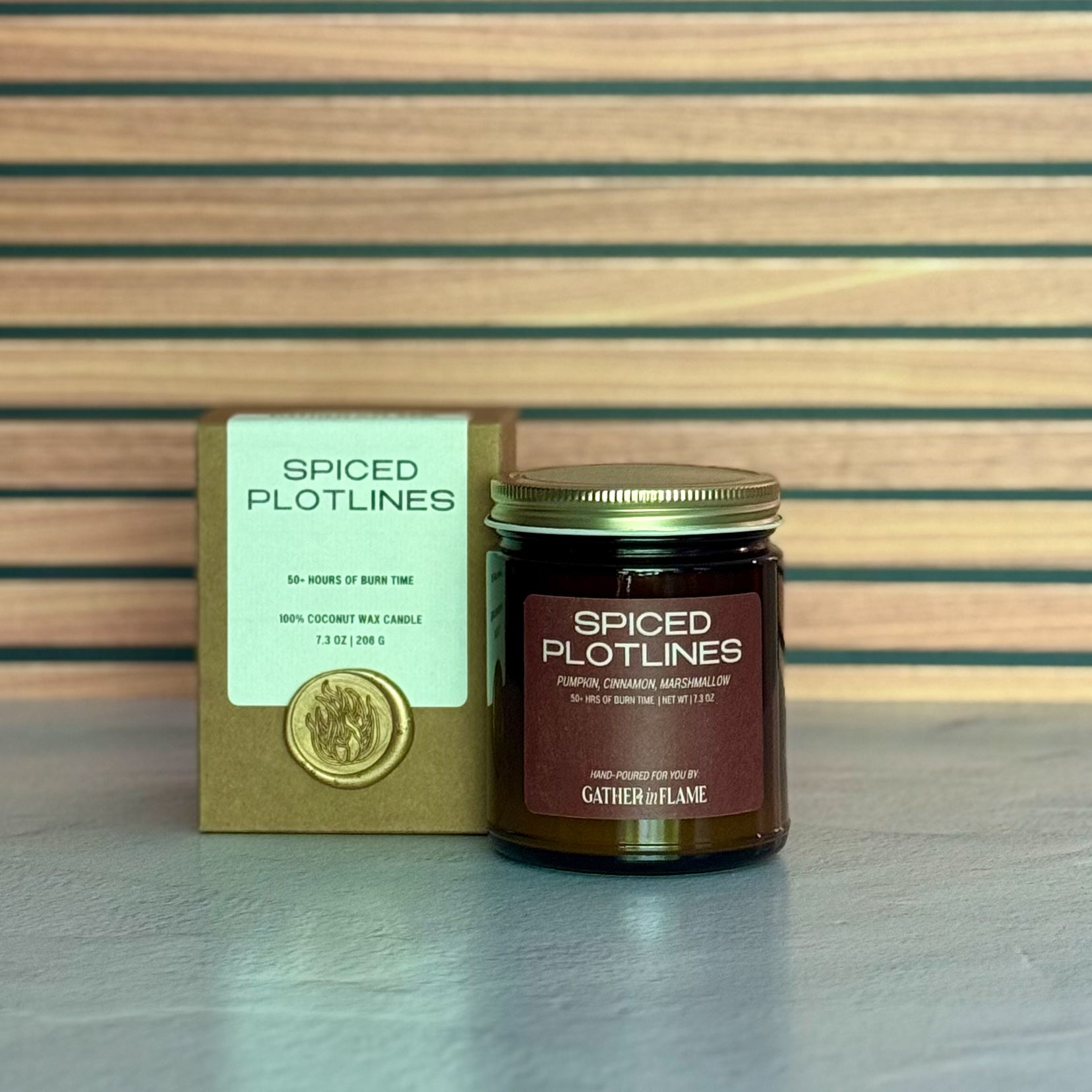 Candle and packaging with 'Spiced Plotlines' branding on a striped background