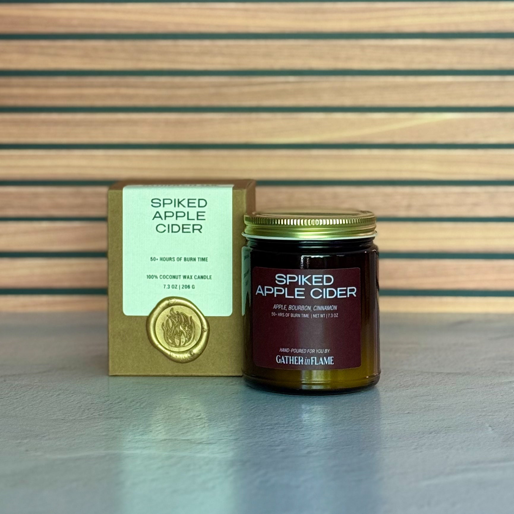 Spiked Apple Cider candle with packaging on a wooden surface