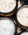 Three candle surfaces with cotton wick and silver and gold glitter. The candles are placed on a light surface.