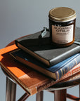 Jar of 'Sugared Citrus' candle on a stack of books with a gray background