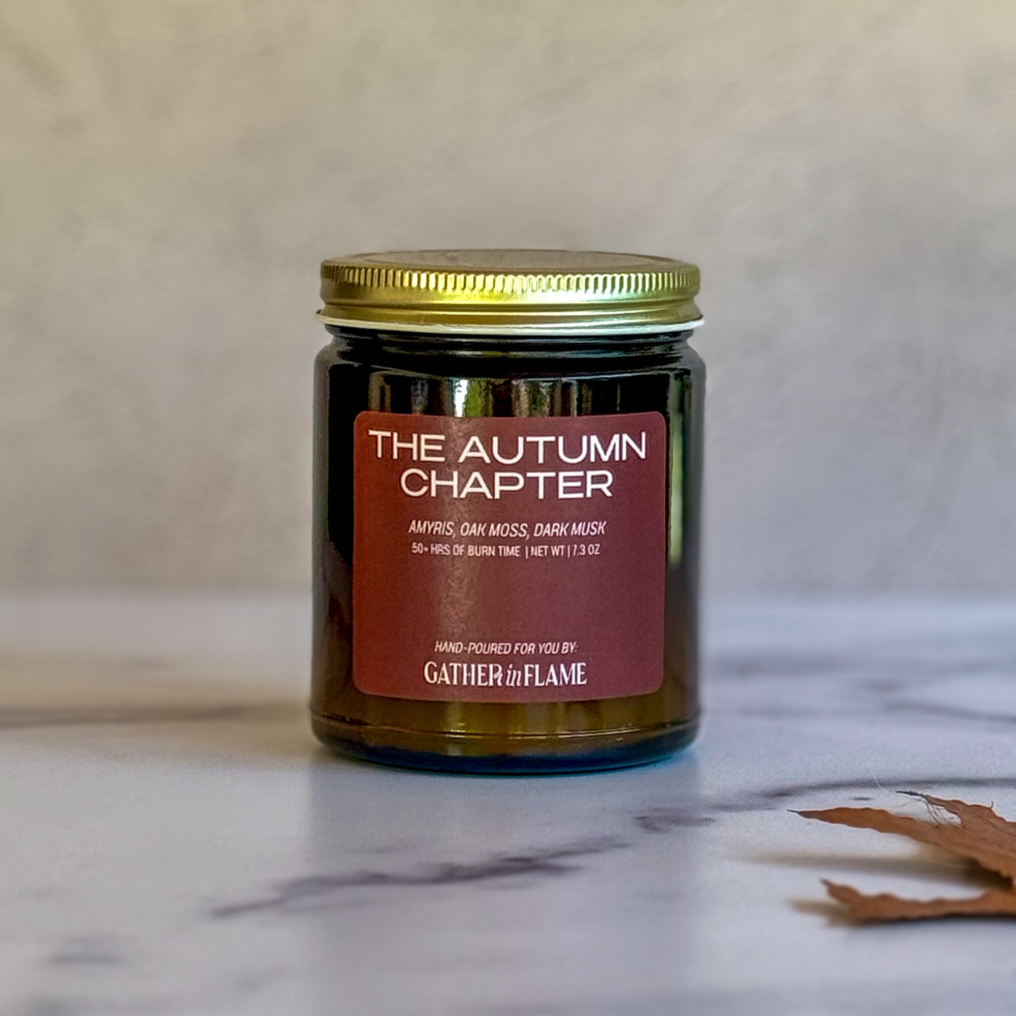 Candle labeled The Autumn Chapter on a light background