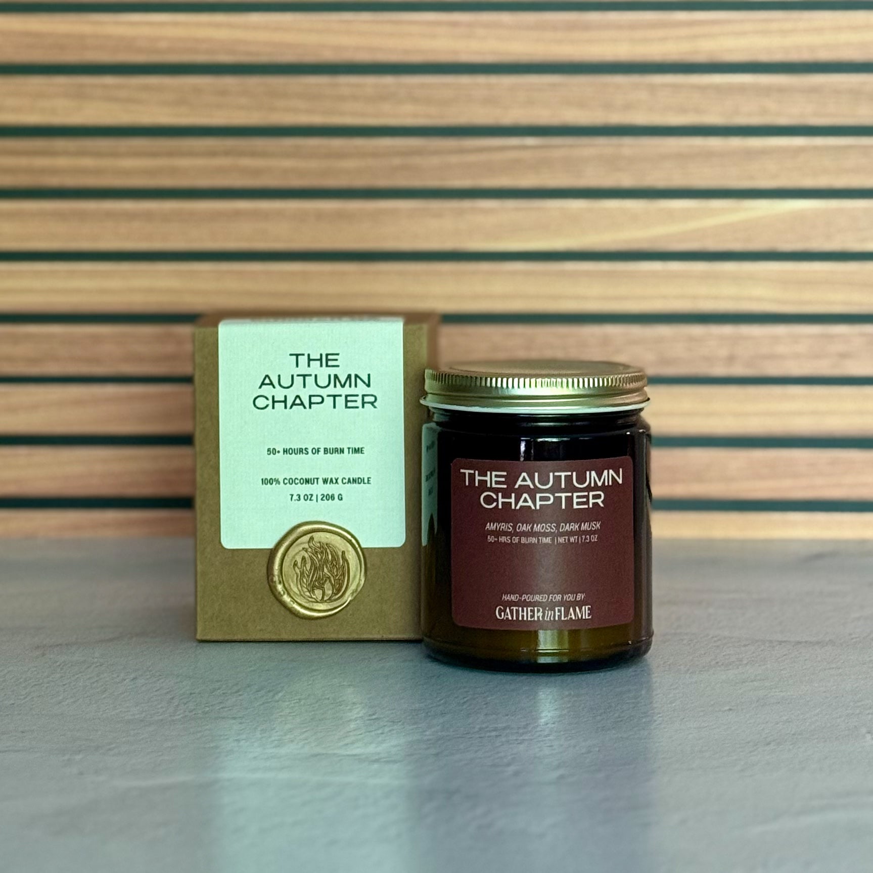 Candle labeled The Autumn Chapter with packaging on a wooden background