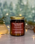 Candle jar with 'Tis the Damn Season label on a festive background