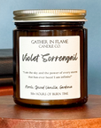Close up of a jar candle with a label reading 'Violet Sorrengail', placed on a wooden stand, with books in the background.