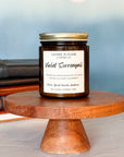 A jar candle with a label reading 'Violet Sorrengail', placed on a wooden stand, with books in the background.